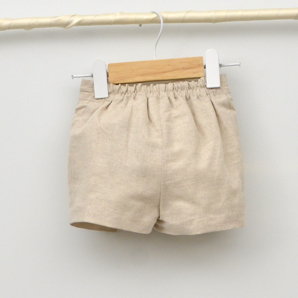 Traje de bautizo para niño en lino color arena con tirantes y camisa blanca, confeccionado en España por Amaya