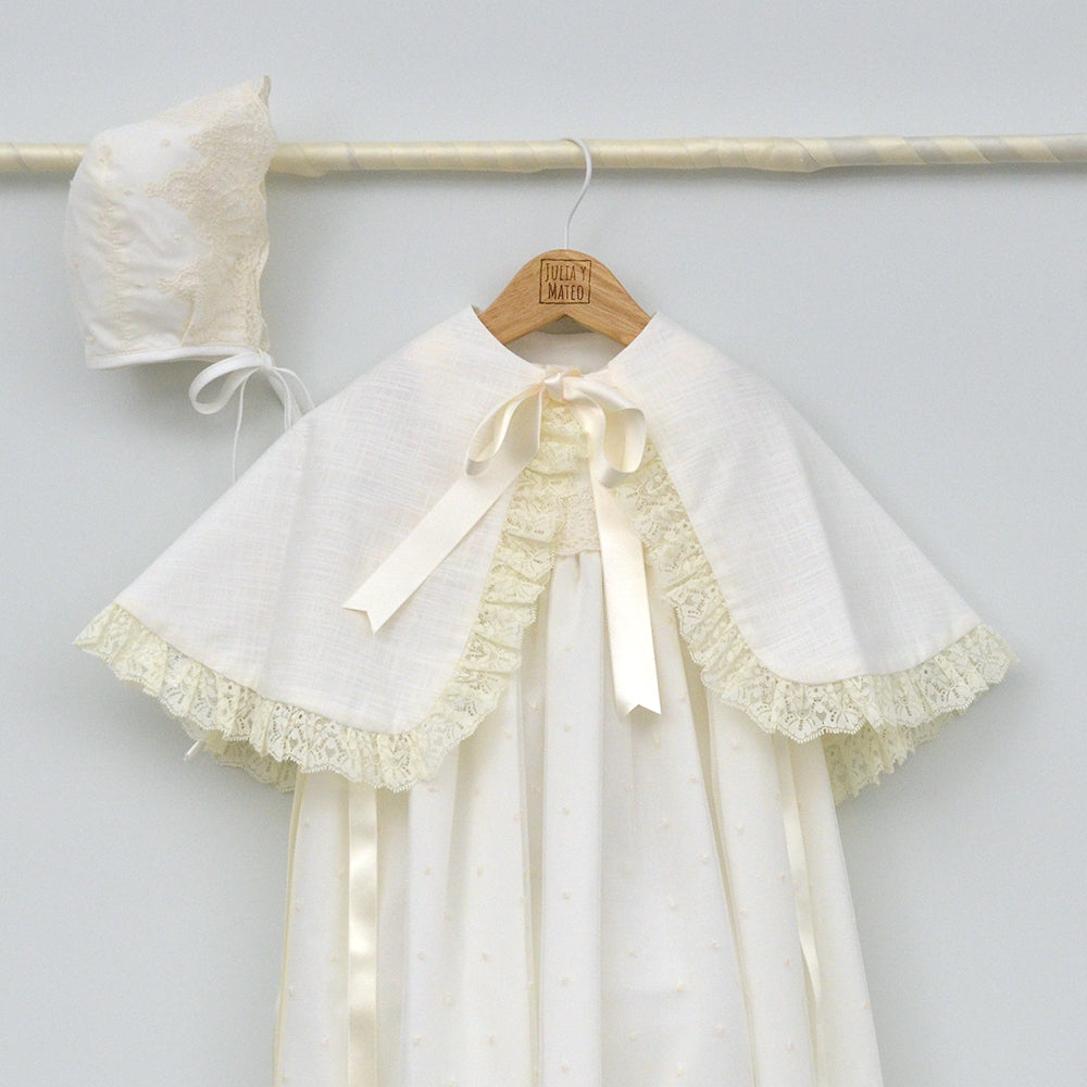 Faldón de bautizo largo en color crema con detalles de encaje y capota a juego, hecho artesanalmente en España