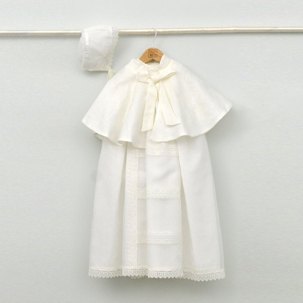 Faldón de bautizo de organza natural con encaje bordado central, remates de puntilla de topos y lazos laterales de cinta de ángel, estilo clasico