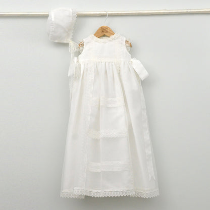 Faldón de bautizo de organza natural con encaje bordado central, remates de puntilla de topos y lazos laterales de cinta de ángel, estilo clasico