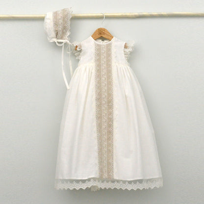 Conjunto de bautizo de la marca Julia y Mateo compuesto por un faldón largo en color blanco roto con franja central de encaje beige, capota a juego y cubrepañal, Primavera 2026