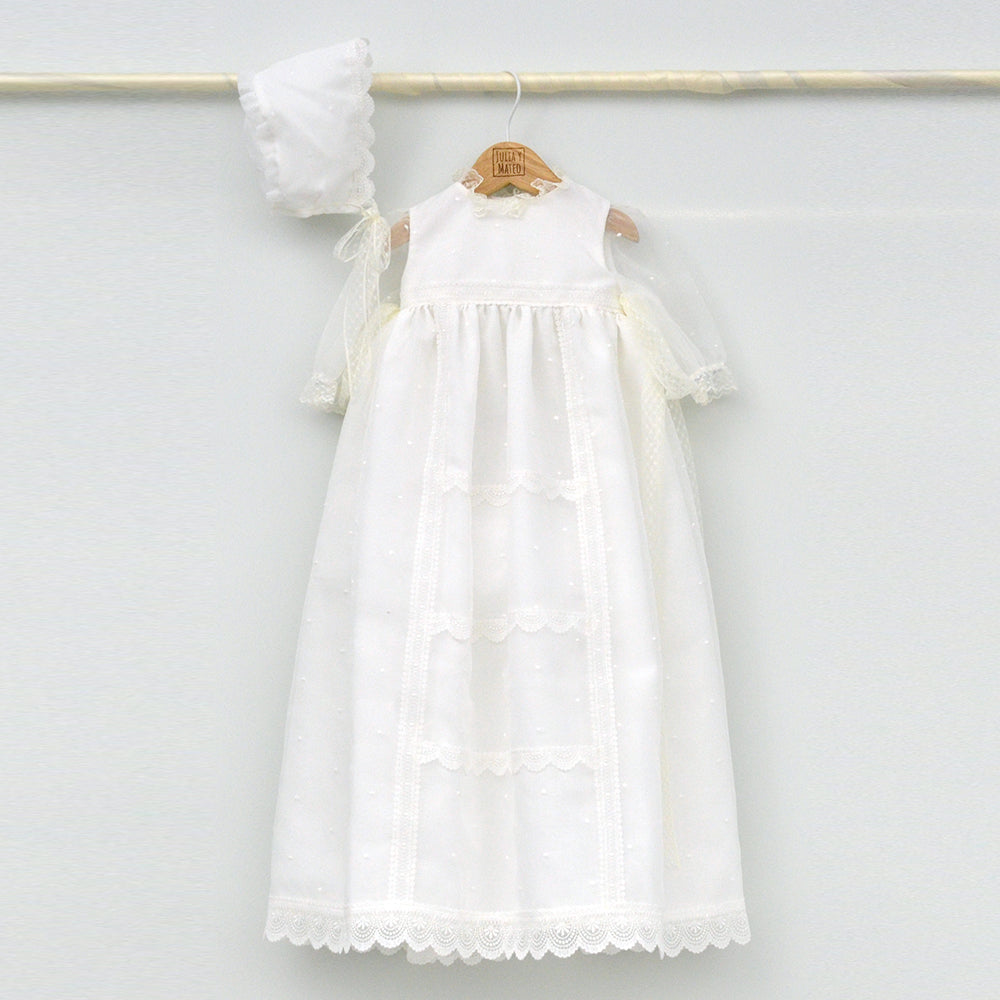 Faldón de bautizo clásico hecho a mano en color blanco, con detalles de encaje de valenciennes, plumeti y capota a juego hecho en la tienda Online JuliayMateo
