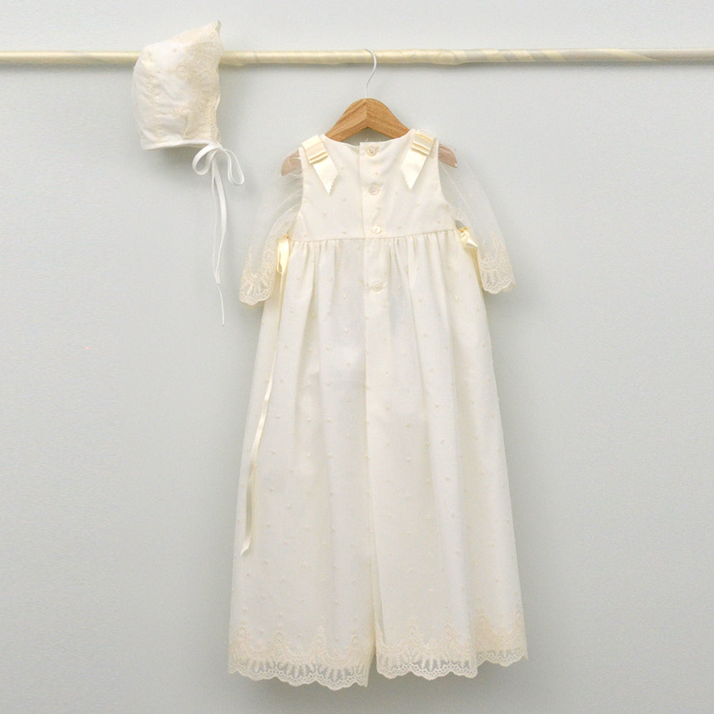 Faldón de bautizo largo en color crema con detalles de encaje y capota a juego, hecho artesanalmente en España